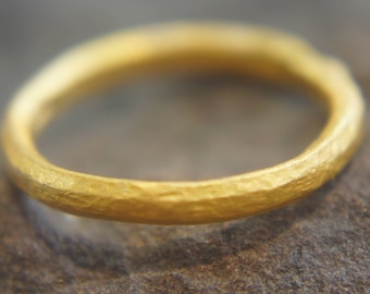 May include: A simple gold band ring with a textured finish.
