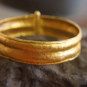 May include: A gold ring with a hammered texture and a double band.