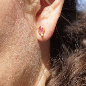 Puede incluir: Un par de pendientes de oro con una peque&ntilde;a piedra ovalada rosa en el centro.