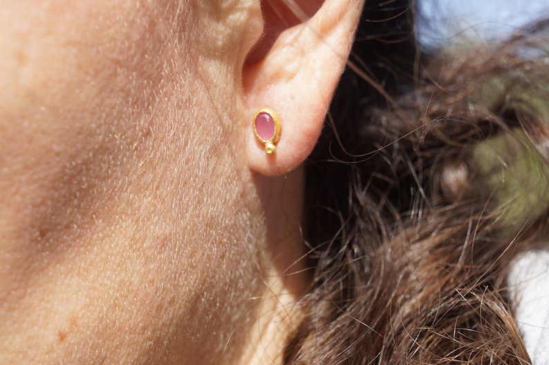 Puede incluir: Un par de pendientes de oro con una peque&ntilde;a piedra ovalada rosa en el centro.