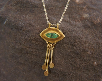 May include: A gold necklace with a green gemstone eye pendant and dangling gold charms.