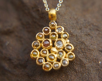May include: A gold pendant necklace featuring a teardrop-shaped cluster of small, faceted diamonds in various shades of yellow, brown, and white.