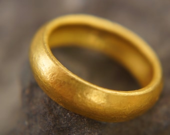May include: A simple gold band ring with a smooth, slightly textured surface.