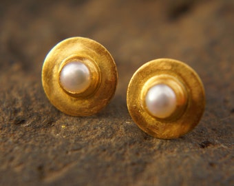 May include: A pair of gold earrings with a pearl in the center of each earring.