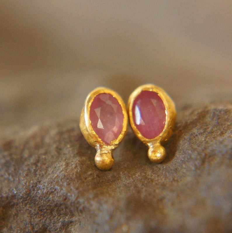 Puede incluir: Un par de pendientes de oro con peque&ntilde;as piedras ovaladas de color rosa. Los pendientes tienen un dise&ntilde;o sencillo y son perfectos para el uso diario.