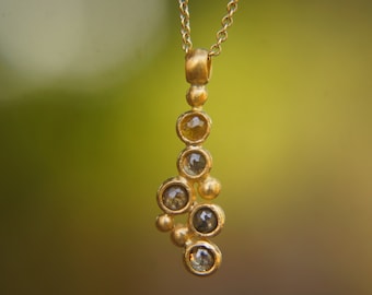 May include: A gold necklace with a pendant featuring a cluster of small, round, faceted gemstones. The gemstones are a mix of clear and yellow.