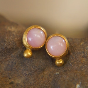 Puede incluir: Un par de pendientes de oro con piedras preciosas rosas. Los pendientes son peque&ntilde;os y delicados, y ser&iacute;an un gran regalo para una ocasi&oacute;n especial.