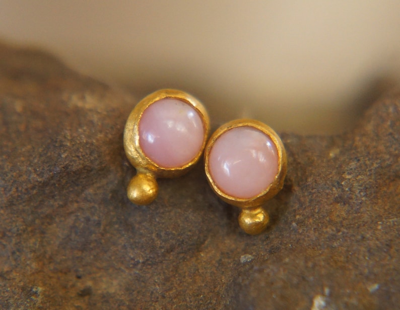 Puede incluir: Un par de pendientes de oro con piedras preciosas rosas. Los pendientes son peque&ntilde;os y delicados, y ser&iacute;an un gran regalo para una ocasi&oacute;n especial.