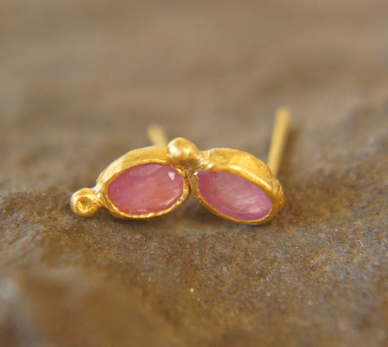 Puede incluir: Un par de pendientes de oro con piedras preciosas ovaladas de color rosa. Los pendientes est&aacute;n engastados en un dise&ntilde;o simple y elegante.