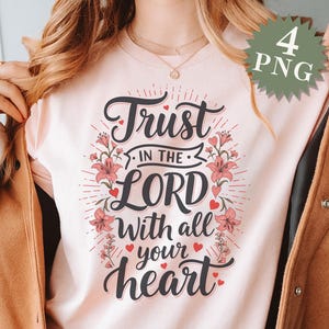 May include: A pink t-shirt with the text "Trust in the Lord with all your heart" in black lettering with pink hearts and floral accents.