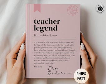 May include: A pink book with the words "teacher legend" in black. The book has a definition and a message about educators. The book is held by a person.