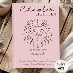 May include: A light pink hardcover book featuring the text Chapter EIGHTEEN at the top, a black line art illustration of a crab zodiac symbol in the center, the text The devoted Cancer Violet below it, and New chapter, new dreams, same beautiful you.