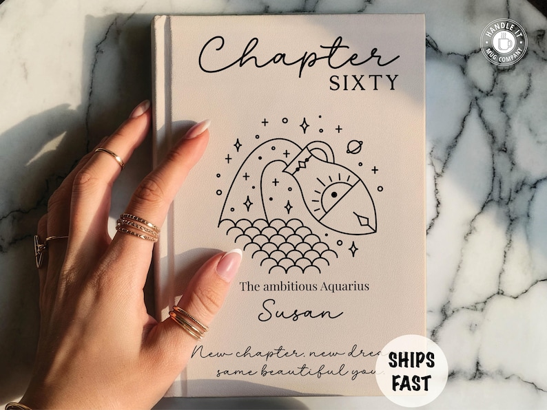 May include: A book cover with the words "Chapter SIXTY" in black script. Below is a black line drawing of an Aquarius symbol. The text "The ambitious Aquarius Susan" is below the drawing. The words "New chapter, new dress, same beautiful you" are at the bottom.