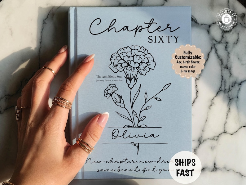 May include: A light blue book cover with the words "Chapter Sixty" in black script. A black floral illustration and the name "Olivia" are featured. The text "New chapter, new dreams, same beautiful you" is at the bottom. The book is customizable.