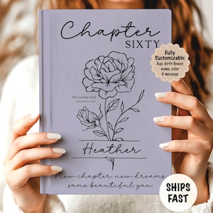 May include: A lavender-colored book with the words "Chapter Sixty" and "Heather" in elegant script. A floral line drawing adorns the cover, with the text "New chapter, new dreams, same beautiful you."