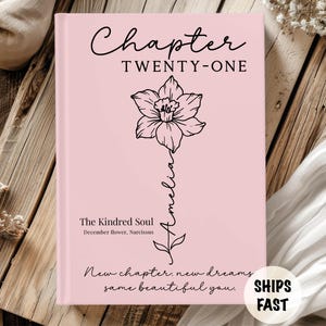 May include: A pink book cover with the text "Chapter TWENTY-ONE" and a black floral illustration. The book also features the text "The Kindred Soul" and "New chapter, new dreams, same beautiful you."