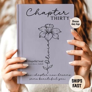 May include: A lavender book cover with the words "Chapter Thirty" and a daffodil illustration. The name "Olivia" is written vertically. Additional text includes "The Hopeful Soul" and "New chapter, new dreams. Same beautiful you."
