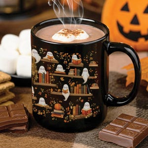 A Halloween cute ghosts reading books pattern mug with a Halloween backdrop of pumpkins and sweets.