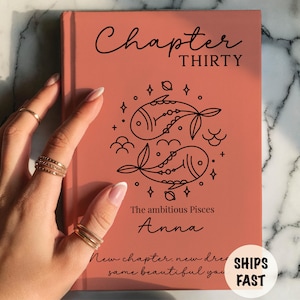 May include: A terracotta-colored hardcover book featuring the black text Chapter THIRTY, a Pisces zodiac fish illustration, the name Anna, and the phrase The ambitious Pisces. Below, the text reads New chapter, new dreams, same beautiful you.