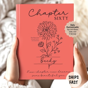 May include: A coral-colored book with the words "Chapter Sixty" in black script. A floral illustration and the name "Becky" are below. Text reads "New chapter, new dreams, same beautiful you." The book is customizable.