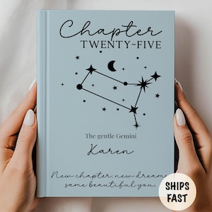 May include: A light blue book cover with the text "Chapter TWENTY-FIVE" and a constellation design. The book is personalized with the name "Karen" and the phrase "New chapter, new dreams, same beautiful you."