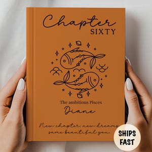 May include: An orange book cover with the words "Chapter SIXTY" in black script. Below is a Pisces design and the name "Diane". The text "New chapter, new dreams, same beautiful you" is also present. A sticker says "SHIPS FAST".