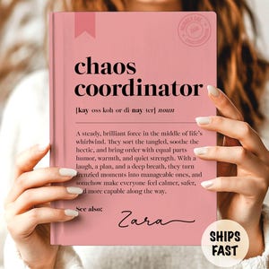 May include: A pink notebook with the words "chaos coordinator" in bold black font. The definition of the term is printed below. The notebook has a pink ribbon bookmark and the name "Zara" is signed at the bottom.