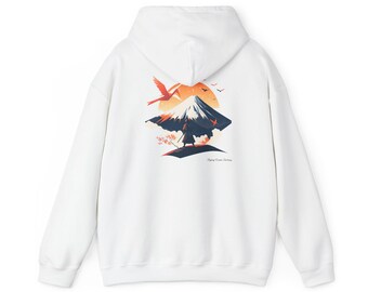May include: White hoodie featuring a graphic of a mountain with a setting sun, birds, and a figure. The design incorporates orange, blue, and black colors. The text "Happy Crane Journey" is printed below the graphic. The hoodie has a hood and long sleeves.