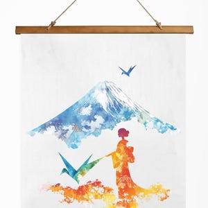 以下が含まれることがあります： 富士山、着物を着た女性、折り鶴を描いた水彩画プリント。アートワークは、青、オレンジ、黄色の鮮やかなカラーパレットを使用しています。プリントは木製のフレームと天然のロープで吊り下げられています。