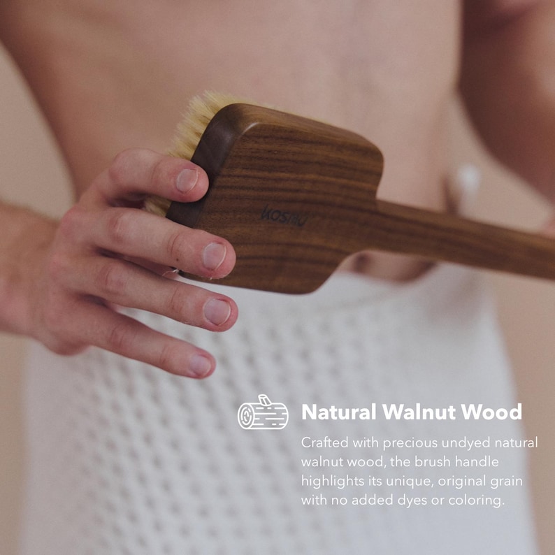 May include: A wooden body brush made of natural walnut wood. The brush has a long handle and a rectangular head with soft bristles. The text "Natural Walnut Wood" is visible.