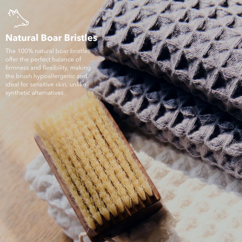 May include: A close-up of a wooden-handled brush with natural boar bristles, alongside folded gray waffle-weave towels. The text "Natural Boar Bristles" is visible. The brush is designed for sensitive skin.