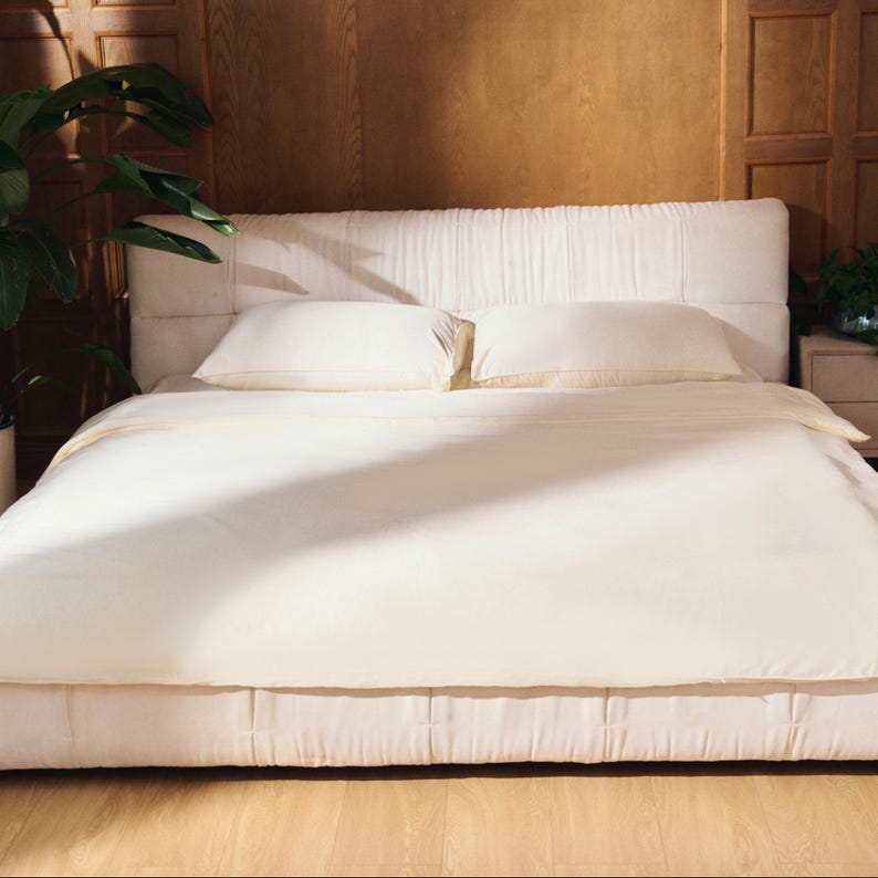 May include: A white upholstered bed with a tufted headboard and a white duvet cover. The bed is made with crisp white linens and pillows.