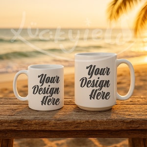 May include: Two white ceramic mugs with the text "Your Design Here" in a black script font. The mugs are on a wooden surface with a beach and sunset background. One mug is smaller than the other.