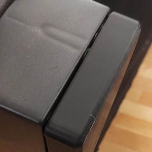 Może przedstawiać: Zbliżenie na czarny skórzany podłokietnik sofy z czarną plastikową osłoną podłokietnika. Osłona jest przymocowana do podłokietnika za pomocą śrub.