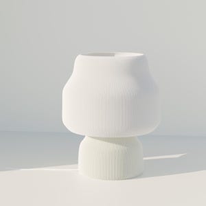 Puede incluir: Un jarrón de cerámica blanco, acanalado, con una base redondeada y una parte superior más ancha y bulbosa. El jarrón tiene un diseño minimalista y un acabado mate. Las estrías verticales añaden textura a la superficie lisa. El jarrón es adecuado para la decoración del hogar.