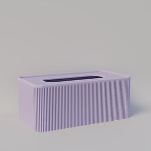 Puede incluir: Un porta pañuelos de tejido de color lavanda con un diseño acanalado. El porta pañuelos tiene una forma rectangular y una ranura para pañuelos.
