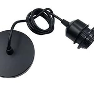 Puede incluir: Una lámpara colgante negra con una placa de techo redonda y un cable enrollado. El accesorio incluye un casquillo negro para una bombilla. El diseño es minimalista y moderno, adecuado para varios estilos de interior.