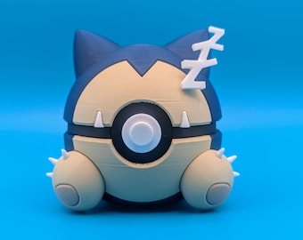May include: A 3D printed figurine of a sleeping Snorlax Pokemon. The figurine is beige and blue with a white Z on its head. The figurine is in a curled up position with its eyes closed.