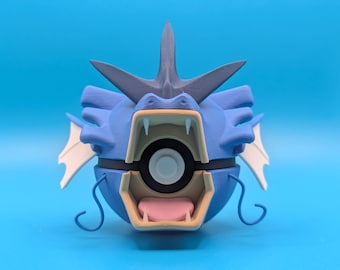 May include: A blue and white 3D printed Pokemon figure of a Gyarados, a water-type Pokemon. The figure is open, revealing a Pokeball inside.