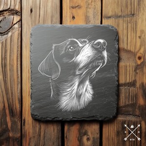 Op de afbeelding: Zwart-witte illustratie van een hondenkop op een zwarte leisteen onderzetter.