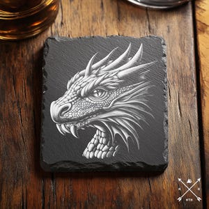 May include: Black slate coaster with a white detailed illustration of a dragon's head.