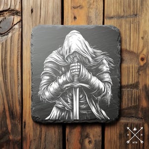 May include: Black and white illustration of a hooded figure holding a sword, printed on a black slate coaster.