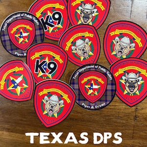 Puede incluir: Un conjunto de pegatinas de Texas DPS en rojo, blanco y azul. Las pegatinas presentan imágenes de osos, perros y la estrella de Texas, con texto como "TEXAS HIGHWAY PATROL". El texto "TEXAS DPS STICKERS" está en la parte inferior.