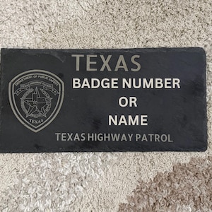 May include: A black rectangular slate sign with the text "TEXAS BADGE NUMBER OR NAME TEXAS HIGHWAY PATROL". The Texas Department of Public Safety badge is on the left side.