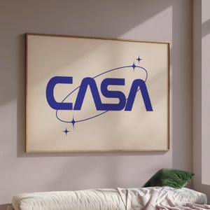 Puede incluir: Un póster blanco con un logotipo azul que dice "CASA" en una fuente retro. El logotipo está rodeado por un círculo azul con tres estrellas blancas.