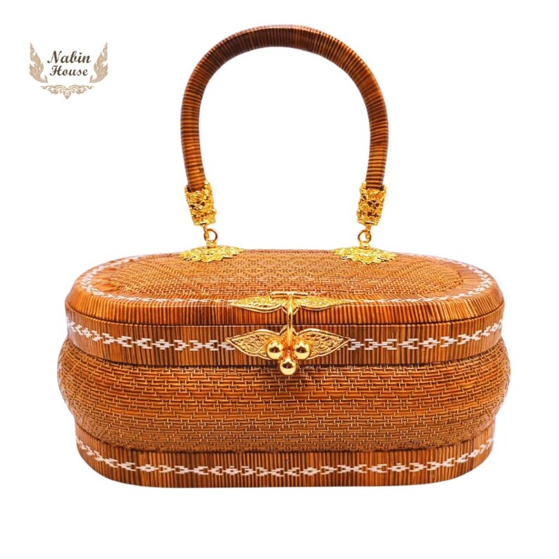 May include: A brown woven oval handbag with a gold handle and clasp. The bag has a white embroidered design around the edges.