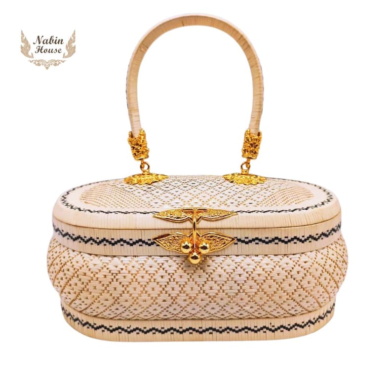 May include: A white woven oval handbag with a gold handle and clasp. The bag has a black and white geometric pattern.