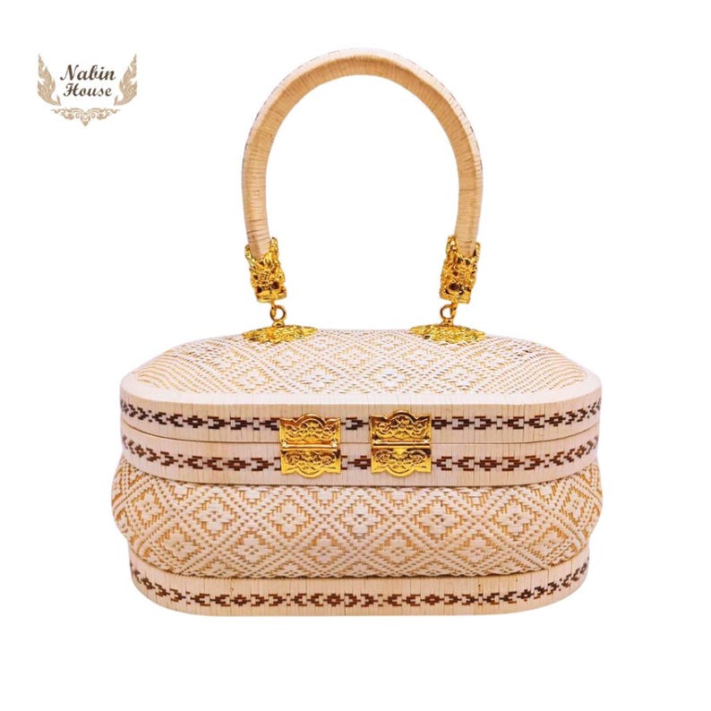 May include: A white woven handbag with a gold handle and gold clasps. The bag has a brown trim and a woven pattern.