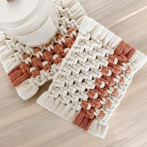 Puede incluir: Dos posavasos de macramé en crema y naranja óxido. Los posavasos tienen un diseño tejido con un borde de flecos. Los posavasos están hechos de una fibra natural suave y son perfectos para agregar un toque bohemio a cualquier decoración.