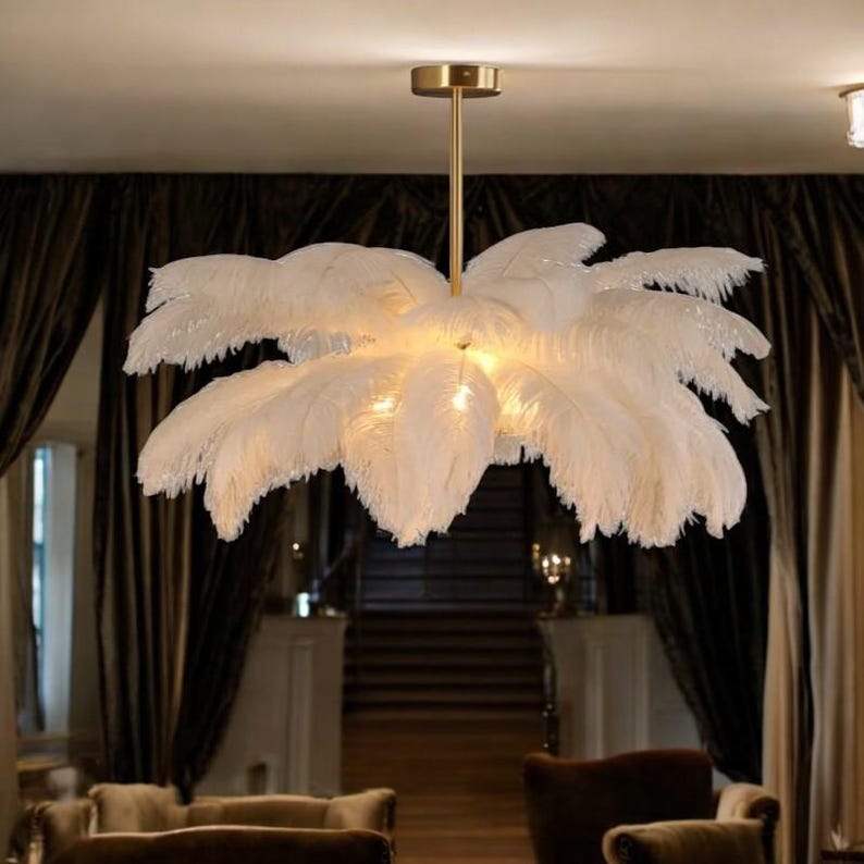 K&ouml;nnte beinhalten: Ein wei&szlig;er Federleuchter mit einem goldenen Metallrahmen. Der Leuchter h&auml;ngt von der Decke und hat ein modernes Design.